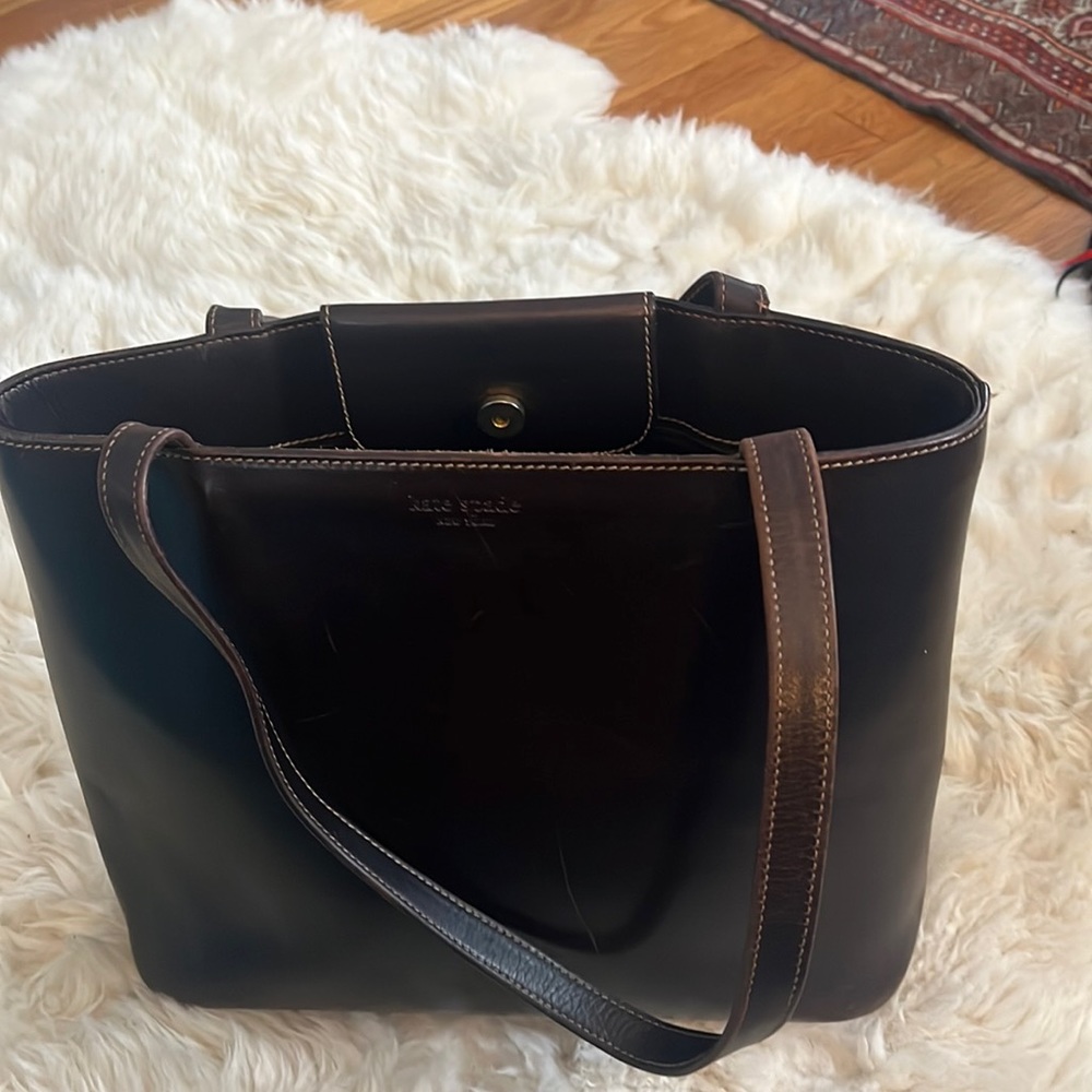 Brown leather Kate Spade Tote w/feet & snap closure. 1 interior zip pocket.